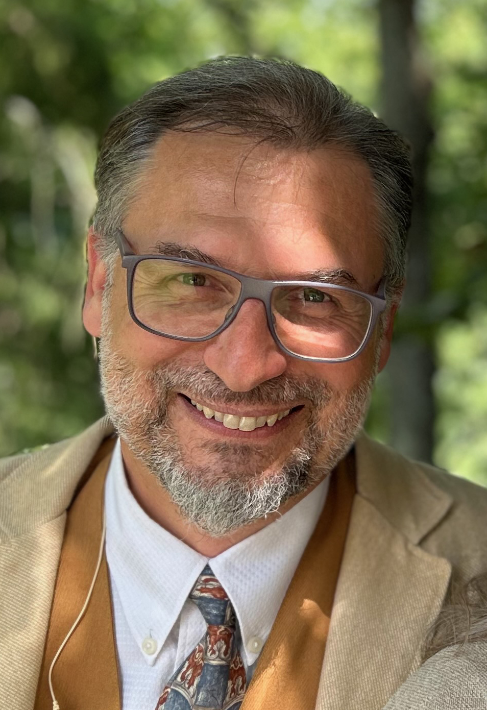 Headshot of Florent in front of a green outdoor background.